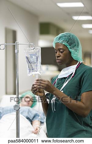 Stock Image - Nurse checking patient's IV drip. Fotosearch