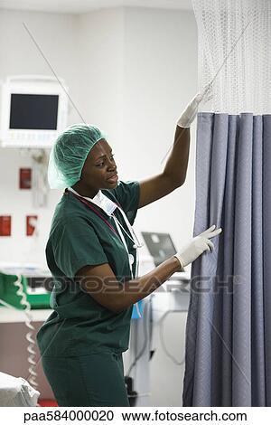 Stock Image - Nurse closing privacy curtain in hospital room. Fotosearch