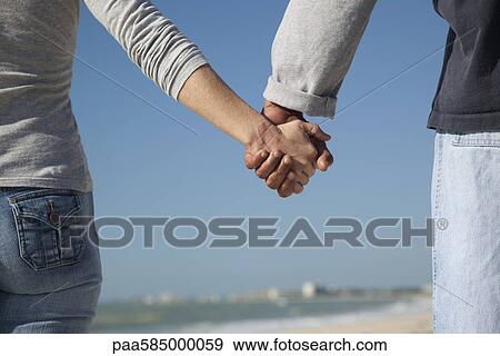 Stock Photo - Couple holding hands outdoors, cropped. Fotosearch