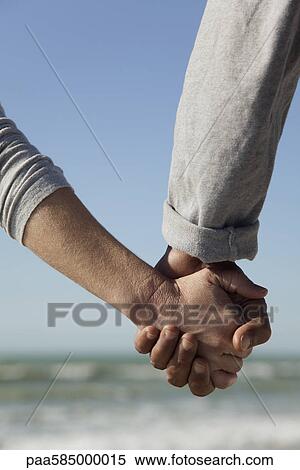 Stock Photography - Couple holding hands outdoors, cropped. Fotosearch