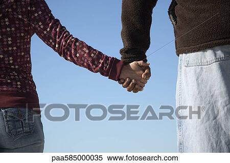 Stock Photography - Couple holding hands outdoors, cropped. Fotosearch