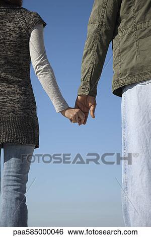 Stock Photograph - Couple holding hands, rear view. Fotosearch