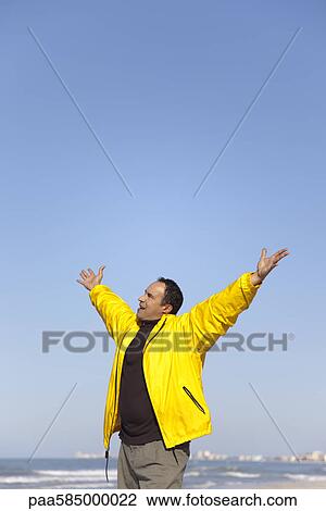 Man at the beach with arms raised in the air View Large Photo Image Stock Image - Man at the beach with arms raised in the air. Fotosearch