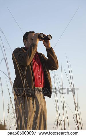 Man looking through binoculars View Large Photo Image Stock Photo - Man looking through binoculars. Fotosearch