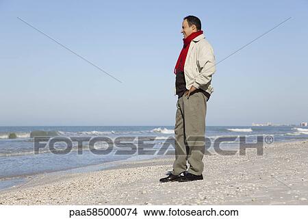 Picture - Man standing on beach looking at view. Fotosearch