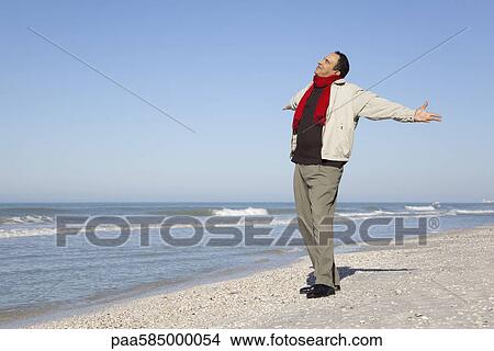 Man standing on beach with arms out and head back View Large Photo Image Picture - Man standing on beach with arms out and head back. Fotosearch