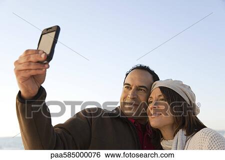 Stock Photograph - Mature couple photographing themselves with photophone. Fotosearch
