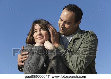 Stock Photo - Mature couple relaxing together outdoors, man caressing woman's hair. Fotosearch