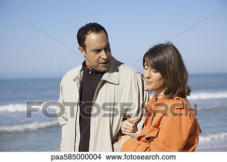 Mature couple walking at the beach and talking together View Large Photo Image Picture - Mature couple walking at the beach and talking together. Fotosearch