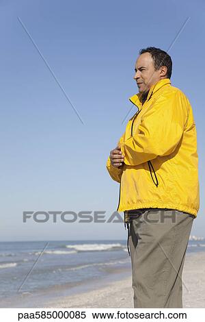 Mature man standing on beach looking at ocean View Large Photo Image Stock Photography - Mature man standing on beach looking at ocean. Fotosearch