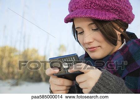 Picture - Teen girl text messaging at the beach. Fotosearch