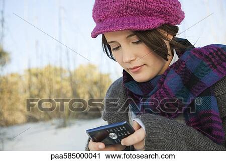 Stock Image - Teen girl text messaging at the beach. Fotosearch