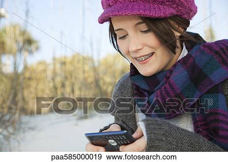 Stock Photo - Teen girl text messaging at the beach. Fotosearch