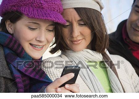 Picture - Teenage daughter showing cell phone to her mother. Fotosearch