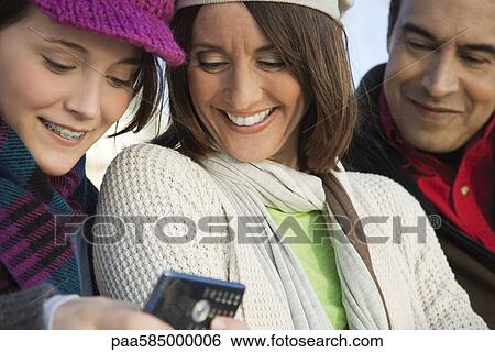 Stock Photograph - Teenage daughter showing cell phone to her parents. Fotosearch