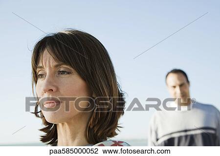 Woman looking away with furrowed brow, man in background View Large Photo Image Stock Image - Woman looking away with furrowed brow, man in background. Fotosearch