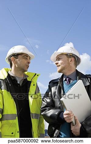 Stock Image - Building contractor and businessman in hard hats. Fotosearch