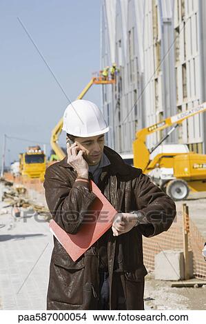 Picture - Building contractor using cell phone, checking time. Fotosearch