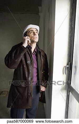 Stock Photo - Building contractor using cell phone. Fotosearch
