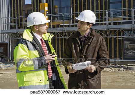 Businessman in hard hat and reflective clothing talking to building contractor View Large Photo Image Stock Photo - Businessman in hard hat and reflective clothing talking to building contractor. Fotosearch