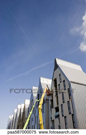 Stock Photography - Construction workers in cherry picker bucket working on building exterior. Fotosearch