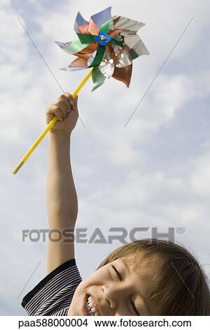 Boy holding pinwheel triumphantly in air View Large Photo Image Picture - Boy holding pinwheel triumphantly in air. Fotosearch