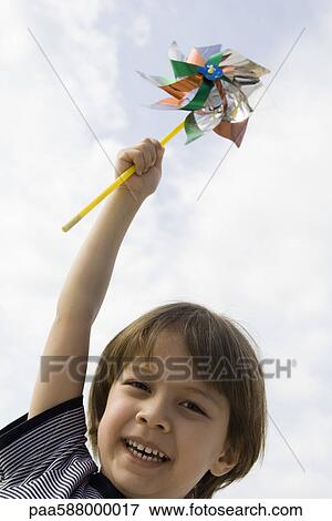 Boy holding up pinwheel outdoors, portrait View Large Photo Image Stock Photo - Boy holding up pinwheel outdoors, portrait. Fotosearch