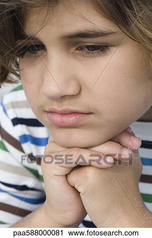 Boy with hands clasped under chin, looking down, portrait View Large Photo Image Stock Image - Boy with hands clasped under chin, looking down, portrait. Fotosearch