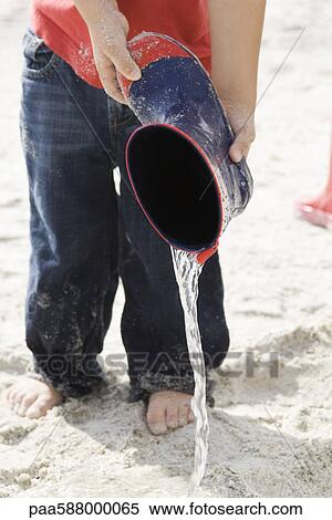 Child pouring water out of rubber boot at the beach View Large Photo Image Stock Photography - Child pouring water out of rubber boot at the beach. Fotosearch