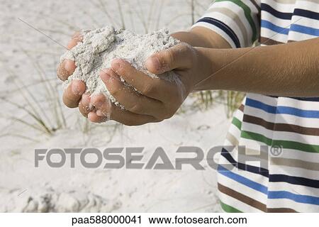 Stock Image - Child scooping sand with hands. Fotosearch