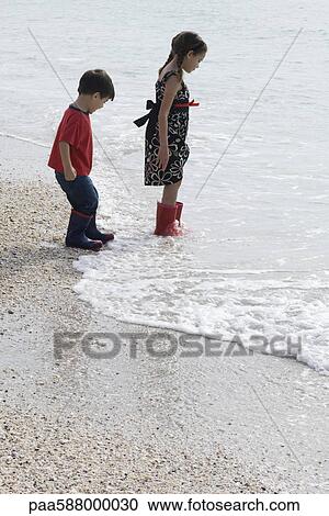 Children wading in surf at the beach View Large Photo Image Stock Image - Children wading in surf at the beach. Fotosearch