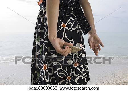 Girl on beach holding seashell behind back, cropped View Large Photo Image Stock Photo - Girl on beach holding seashell behind back, cropped. Fotosearch