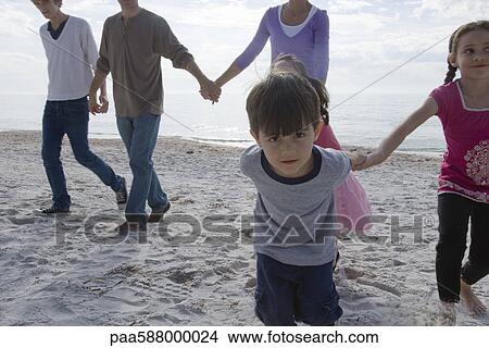 Group of people holding hands and walking on beach View Large Photo Image Picture - Group of people holding hands and walking on beach. Fotosearch