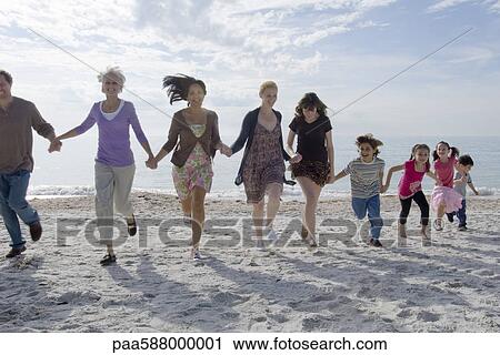 Group of people holding hands and running on beach View Large Photo Image Stock Image - Group of people holding hands and running on beach. Fotosearch