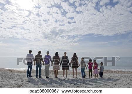 Group of people standing on beach, holding hands View Large Photo Image Stock Photo - Group of people standing on beach, holding hands. Fotosearch