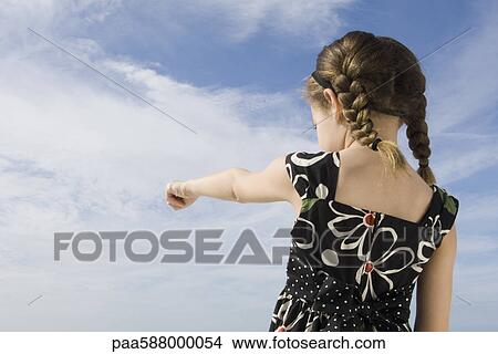 Picture - Little girl pointing at the sky, rear view. Fotosearch