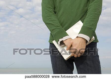 Male standing on beach with book in hands, cropped View Large Photo Image Stock Photo - Male standing on beach with book in hands, cropped. Fotosearch