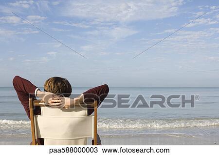 Stock Image - Relaxing in chair at the beach, looking at view. Fotosearch