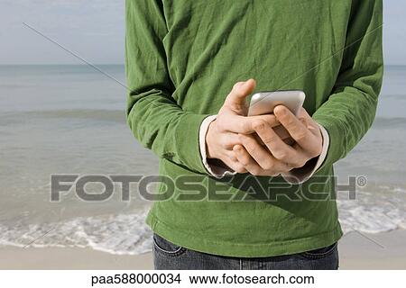 Text messaging at the beach View Large Photo Image Picture - Text messaging at the beach. Fotosearch