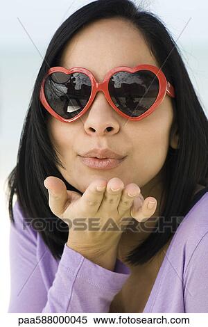 Woman wearing heart shaped sunglasses, blowing a kiss at camera View Large Photo Image Stock Photography - Woman wearing heart shaped sunglasses, blowing a kiss at camera. Fotosearch