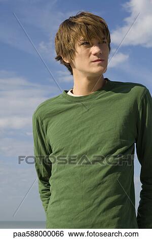 Young male outdoors, looking away in thought, portrait View Large Photo Image Stock Photograph - Young male outdoors, looking away in thought, portrait. Fotosearch