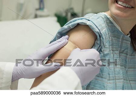 Stock Photograph - Doctor applying adhesive bandage to patient's arm. Fotosearch