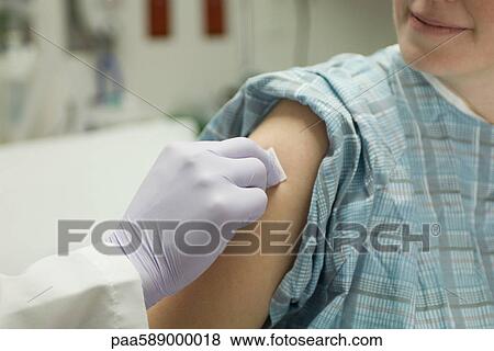 Doctor cleaning patient's arm with alcohol swab in preparation for a shot View Large Photo Image Stock Photo - Doctor cleaning patient's arm with alcohol swab in preparation for a shot. Fotosearch