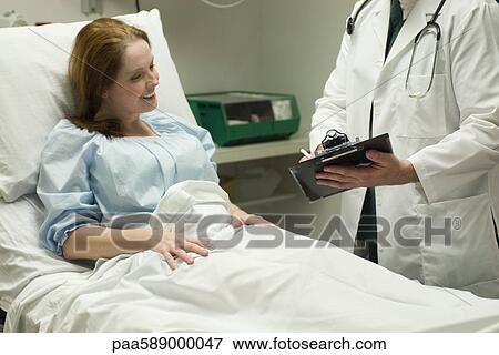 Doctor going over chart with patient in hospital View Large Photo Image Stock Photo - Doctor going over chart with patient in hospital. Fotosearch