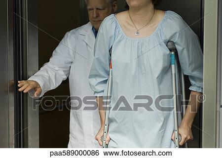 Doctor holding elevator door for patient using crutches View Large Photo Image Stock Photograph - Doctor holding elevator door for patient using crutches. Fotosearch