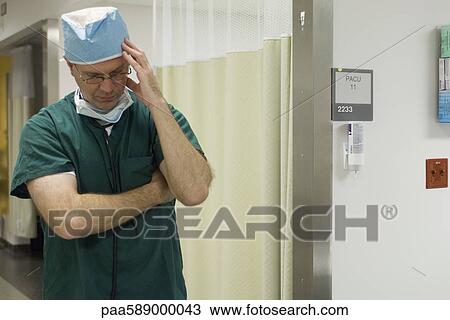 Doctor holding head and looking down View Large Photo Image Stock Image - Doctor holding head and looking down. Fotosearch