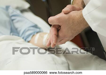 Doctor holding patient's hand, cropped View Large Photo Image Stock Photograph - Doctor holding patient's hand, cropped. Fotosearch