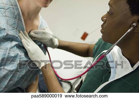 Doctor listening to patient's chest with stethoscope View Large Photo Image Stock Photo - Doctor listening to patient's chest with stethoscope. Fotosearch