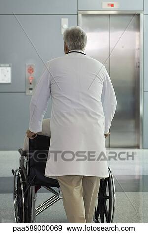 Doctor pushing patient in wheelchair View Large Photo Image Stock Photo - Doctor pushing patient in wheelchair. Fotosearch