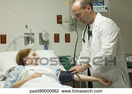 Doctor putting blood pressure cuff on patient in hospital View Large Photo Image Stock Image - Doctor putting blood pressure cuff on patient in hospital. Fotosearch